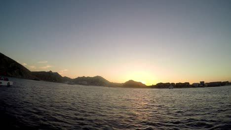 View-of-a-city-on-the-coast-at-sunset,-from-a-boat-on-the-ocean