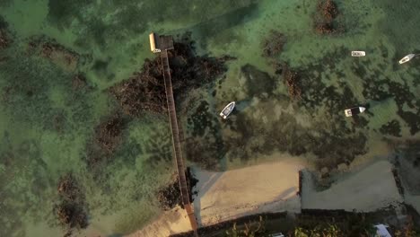 Resort-coast,-wooden-pier-and-boats-in-ocean.-Aerial-view