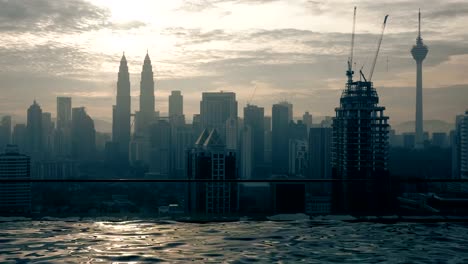 Time-lapse-view-of-swimming-pool-on-the-skyscraper-roof-against-sunrise-building-cityscape.-Kuala-Lumpur,-Malaysia