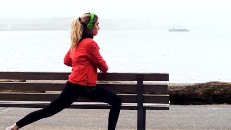 Woman-performing-stretching-exercise-at-seaside-4k