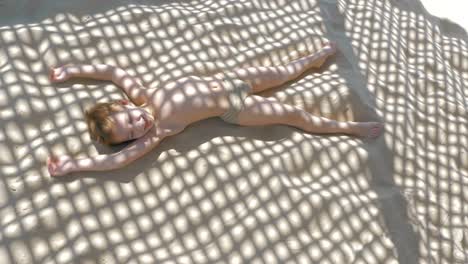 Child-making-sand-angel-when-relaxing-on-the-beach