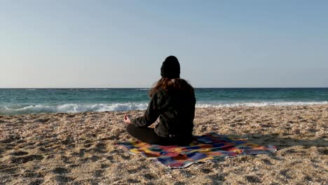 Girl-meditates-on-the-shore-of-the-Mediterranean-Sea-on-a-cool-autumn-day.