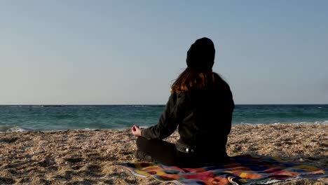 Girl-meditates-on-the-shore-of-the-Mediterranean-Sea-on-a-cool-autumn-day.