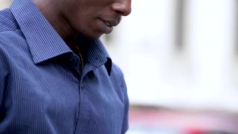 Relaxed-black-african-man-in-the-street-typing-on-his-digital-tablet