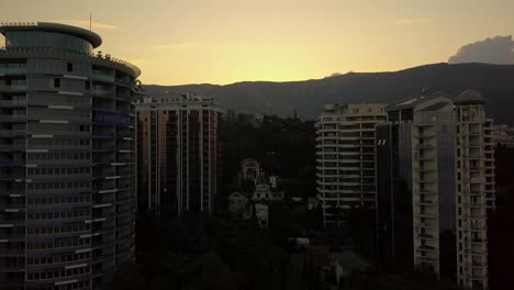 silhouette-of-tall-skyscraper-living-buildings-apartments-on-a-sunset-time-in-near-the-mountains-and-clouds-above