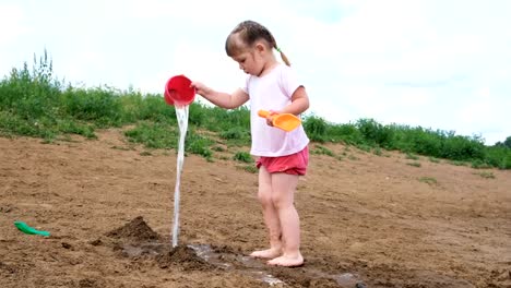 Niña-vierte-agua-de-un-balde-en-la-arena.-Niño-jugando-en-la-playa