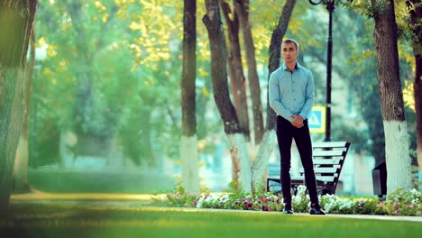 Handsome-young-man-is-waiting-for-someone-in-the-park-in-the-summer-or-in-the-spring