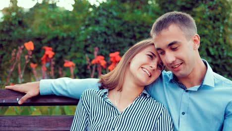 Pareja-joven-feliz-en-el-amor-sentado-en-un-banco-del-parque