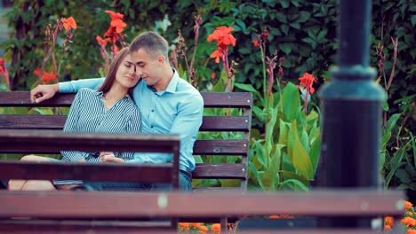 Attractive-couple-sitting-on-bench-in-park