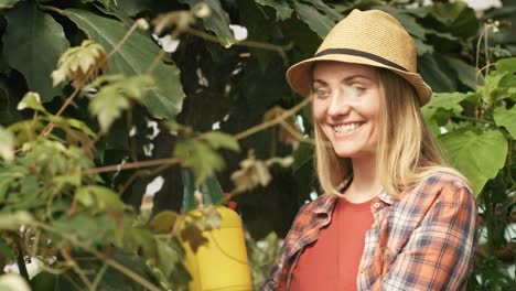 Mujer-feliz-rociando-las-plantas-en-invernadero