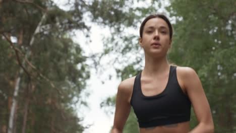 Sporty-Young-Woman-Running-along-Forest-Road