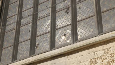 Verglasung-der-alten-Kathedrale-Fensterglas-mit-Reflexionen-von-Licht-langsam-Tilt-4K