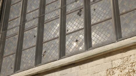 Acristalamiento-de-vidrio-de-ventana-de-Catedral-Antigua-con-reflejos-de-luz-lenta-inclinación-4K