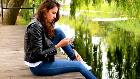 Woman-using-mobile-phone-near-river-4k