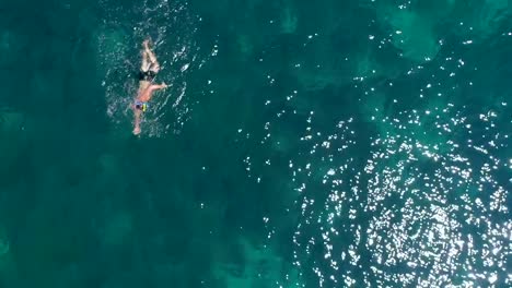 Vista-aérea-del-hombre-nadando-en-el-mar-de-la-isla-de-Kioni,-Grecia
