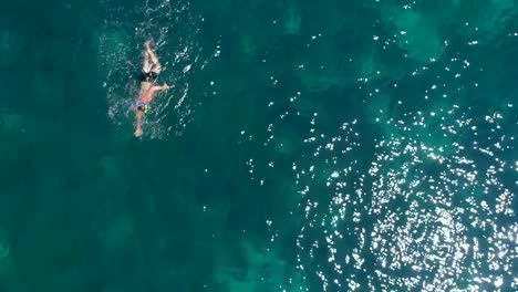 Aerial-view-of-man-swimming-in-the-sea-of-Kioni-island,-Greece