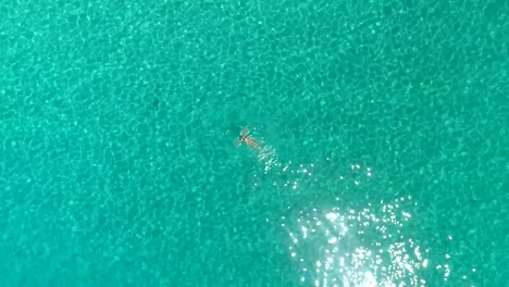 Vista-aérea-de-una-mujer-nadando-en-el-mar-de-la-isla-de-Atokos,-Grecia