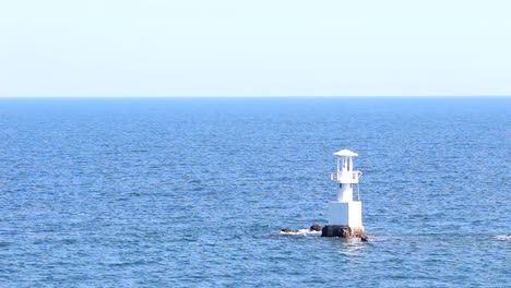 Leuchtturm-im-Meer,-mit-blauem-Himmel