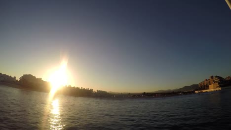 Vista-de-la-ciudad-en-la-costa-al-anochecer,-de-un-barco-en-el-mar