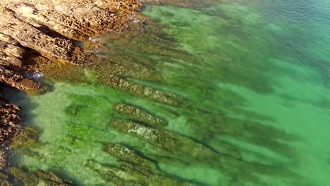 Emerald-ocean-wave-on-a-rocky-beach-aerial-view