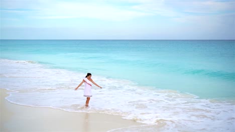 Schöne-junge-Frau-am-Strand-zu-Fuß-in-seichtem-Wasser.