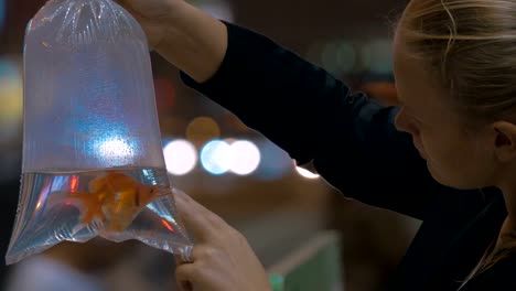 Woman-holds-in-hand-plastic-package-with-aquarium-gold-fish-in-the-shopping-mall.-Hong-Kong,-China