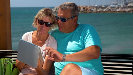 Senior-couple-using-touch-pad-on-waterfront