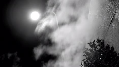 Steam-against-street-lantern-light-at-night,-mystic-black-and-white-shot