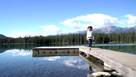 Mujer-caminando-sobre-pie-de-muelle-sobre-el-impresionante-lago-de-montaña-en-las-Rocosas-canadienses