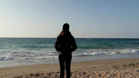 Girl-is-standing-on-the-shore-of-the-Mediterranean-Sea-on-a-cold-autumn-day