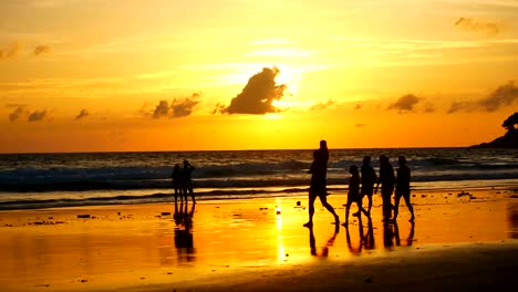 Silhouette-Touristengruppen-sind-Fuß-am-Strand-bei-Sonnenuntergang-beim-Entspannen-am-tropischen-Strand-vor-der-Monsunzeit-mit-Sonnenuntergang-Hintergrund-in-der-Natur-und-Reisen-Konzept.