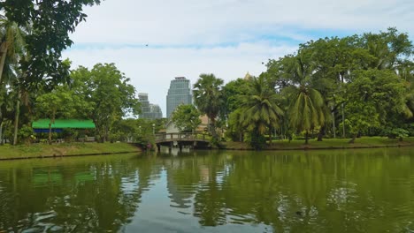 puente-a-través-de-un-lago-en-un-parque-con-vistas-a-la-zona-de-negocios-metropolitana