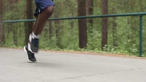 Piernas-del-hombre-de-negro-corre-a-lo-largo-de-camino-forestal