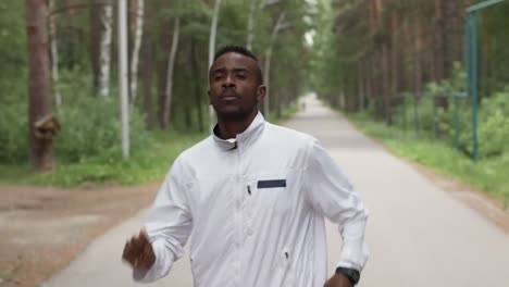 Black-Man-in-Windbreaker-Jogging-in-Forest