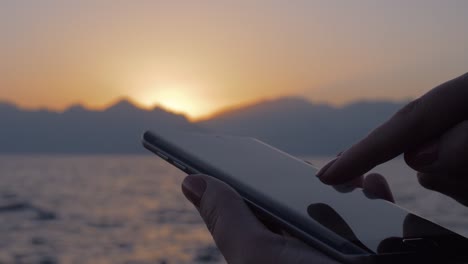 Frau-mit-Handy-auf-Meer-und-Sonnenuntergang-Hintergrund