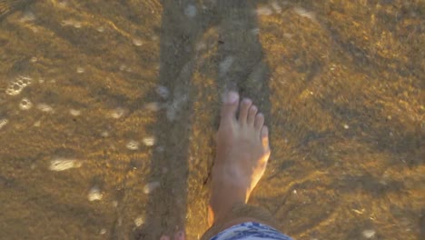 Vacationer-walking-along-the-sea-coast-and-waves-washing-his-feet