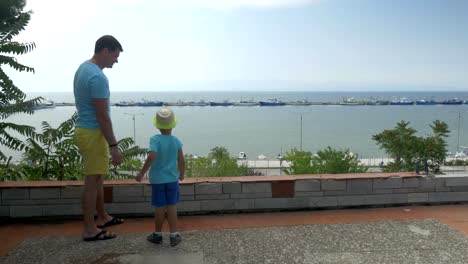Junger-Mann-und-Sohn-sind-Felsen-gegen-Boote-Hafen-in-Piräus,-Griechenland-Meer-werfen.