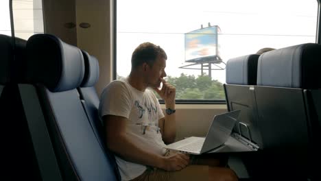 Vista-de-la-joven-viajaba-en-el-tren-y-trabajando-con-el-portátil-sobre-la-mesa-contra-la-ventana,-Países-Bajos