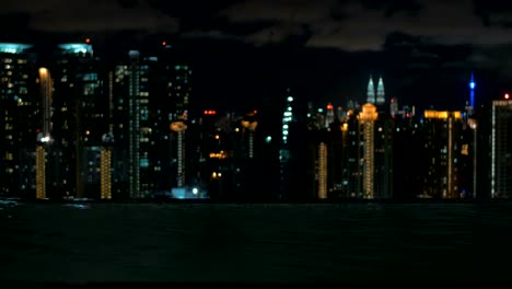 Blick-auf-Frau-Schwimmen-im-Pool-auf-dem-Dach-des-Wolkenkratzers-gegen-Nacht-Stadtlandschaft.-Kuala-Lumpur,-Malaysia