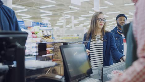 At-the-Supermarket:-Checkout-Counter-Cashier-Scans-Groceries-and-Food-Items.-Customers-Place-Products-on-Conveyor-Line.-Clean-Modern-Shopping-Mall.