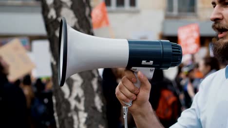 Junger-erwachsener-Mann-schreit-im-Megaphon.-Kaukasische-Menschen-schreien-heftig-und-wütend.