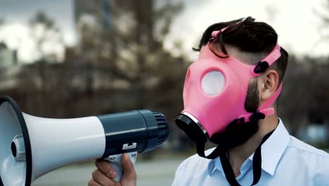 Caucasian-man-in-a-pink-gas-mask-shouts-into-a-megaphone-close-up-4k.