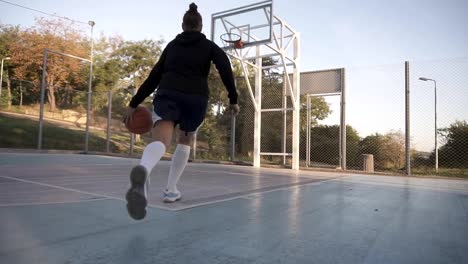 Seltener-Blick-auf-ein-junges-Mädchen-Basketball-Spieler,-training-und-Bewegung-in-der-Natur-auf-das-Amtsgericht.-Mit-dem-Ball-dribbeln,-Prellen-und-machen-einen-Schuss.-Niedrigen-Winkel-Aufnahmen