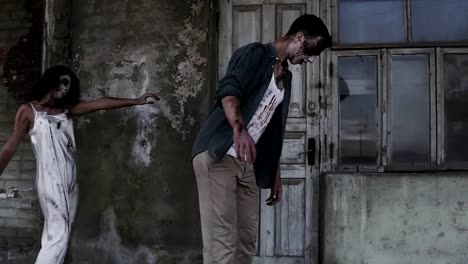 Concepto-de-horror-de-Halloween.-Foto-de-fantasma-espeluznante-de-macho-y-hembra-o-zombie-caminando-con-heridos-cara.-Una-vieja-casa-abandonada-en-el-fondo