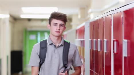 Portrait-Of-Male-High-School-Student-Walking-Down-Corridor-And-Smiling-At-Camera