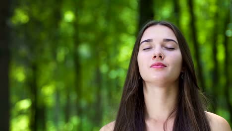 Jovencita-en-el-bosque-siente-la-naturaleza-con-sonrisas-de-ojos-cerrados,-unidad-de-sentidos