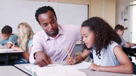 Male-elementary-school-teacher-working-in-class-with-girl