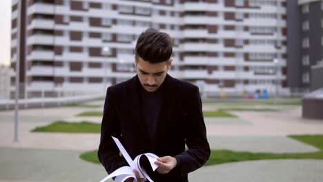 Attractive-businessman-walking-and-throw-out-documents-against-business-building-background