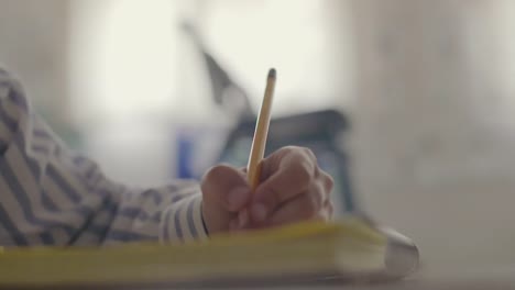 Schüler-männliche-Hand-schreiben-Copybook-In-weißen-Raum-Bildungskonzept