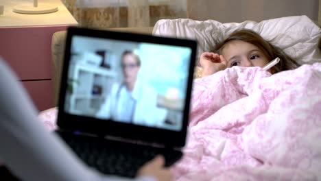 Mom-with-a-little-sick-daughter-gets-a-doctor's-consultation-using-video-chat-at-home.